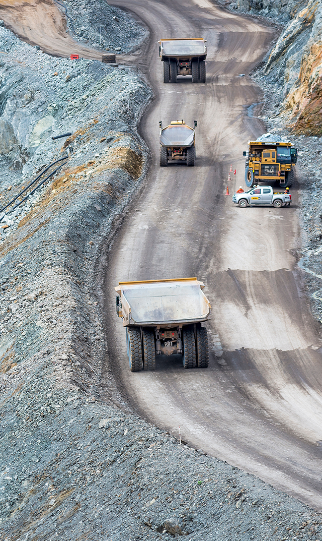FS24-who-01 Several mining haul trucks working in an open pit mine.